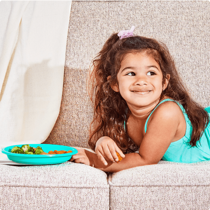 Child laying on a sofa with a Little Spoon plates meal