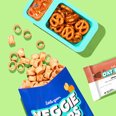 Assorted Little Spoon snacks on a green background, one of which is open