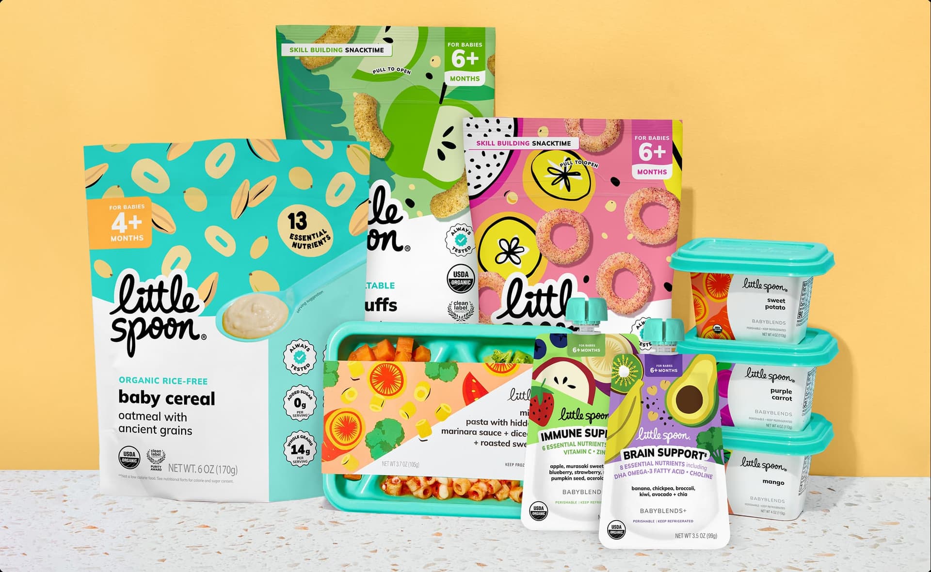 Little Spoon product lineup, including organic oatmeal baby cereal, kale apple curls, banana papaya rings, a Biteables tray, and assorted Babyblends containers, arranged against a yellow background.