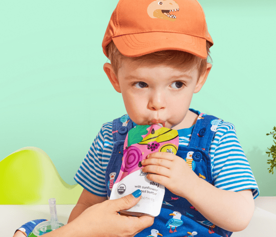 A young boy slurps on a Little Spoon Sun Butter and Jelly Smoothie with the help of a parent.