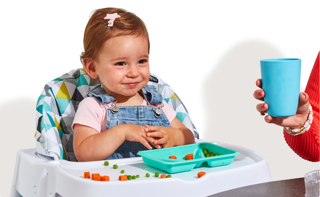 An 18 month old girl sits in a high chair with a tray of Little Spoon Biteables, which contain small-diced pieces of vital vegetables and proteins for young eaters.
